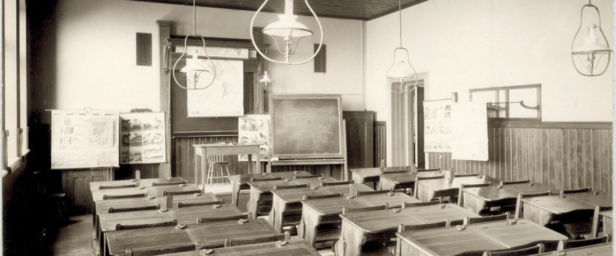 Klassrum i Oscar Fredriks Folkskola från 1901 med träbänkar och tavla