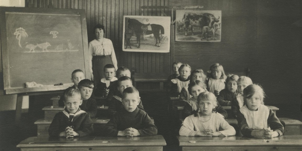 Närmare 20 yngre elever i ett klassrum med lärarinna bakom.